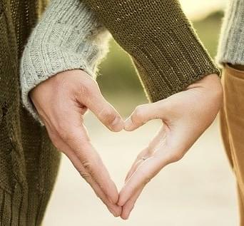 a couple touching hands with fingers forming a heart