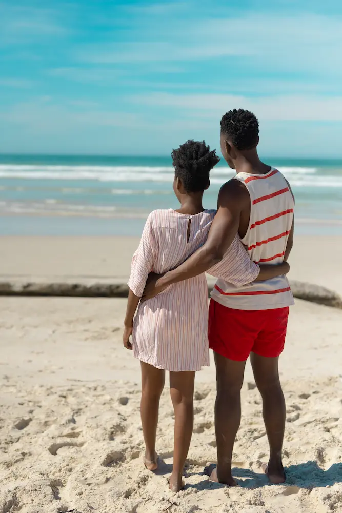 Rear-view-of-african-american-young-couple - Finding Peace Counseling Service PLLC Rear view of african american young couple with arms around looking at sea while standing on beach