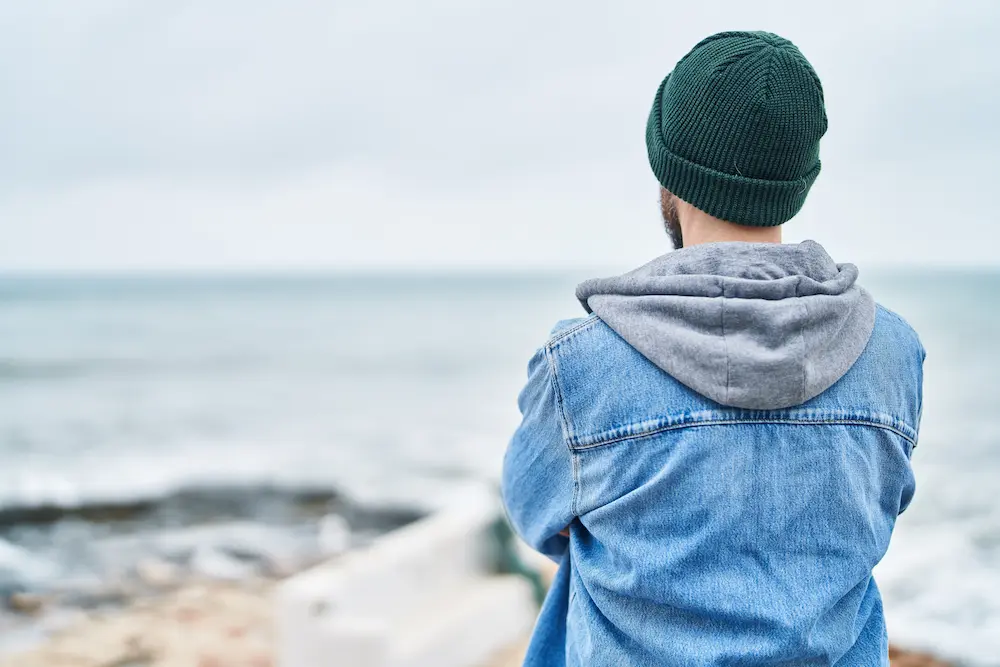 Young-bald-man-standing-on-back-view-at-seaside - Finding Peace Counseling Service PLLC Young bald man standing on back view at seaside