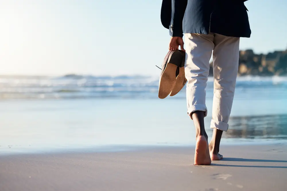 a-business-man-walking-in-the-sand-by-the-sea-or-ocean - Finding Peace Counseling Service PLLC Walking, beach and mental heath with a business man walking in the sand by the sea or ocean after work.