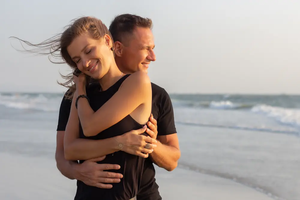 laughing and holding hands on a deserted tropical beach at sunset